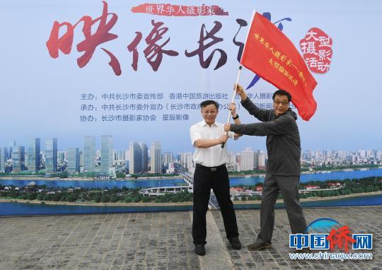 中共长沙市委宣传部副部长朱锦辉（图左）向世界华人摄影家代表王文澜授旗。 杨华峰 摄