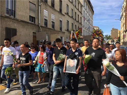 张朝林之子捧着父亲遗像与华人同胞一起上街请愿。(法国《欧洲时报》/黄冠杰 摄)