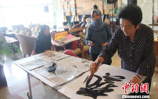 图为在印尼全国性的艺术展览上，李惠珠挥毫创作。 林永传 摄