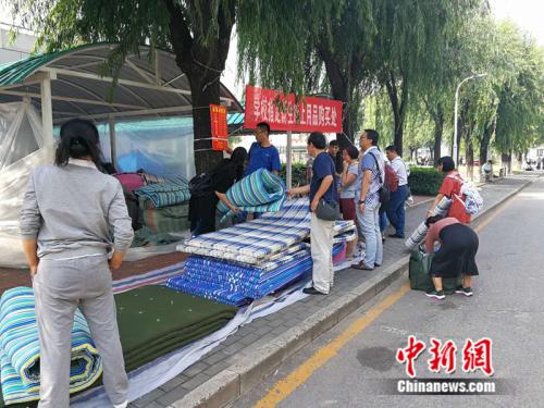 资料图：2017年8月30日，首都师范大学部分院系迎来新生报到。图为学生家长帮孩子购买开学用品。 中新网记者 张尼 摄