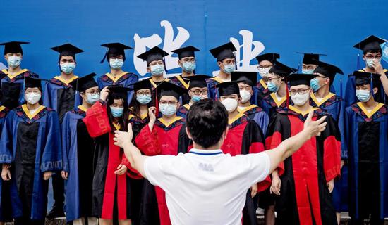 6月11日，湖北武汉华中科技大学校园内，老师组织毕业生拍摄毕业照。6月中旬，武汉高校毕业生陆续返校，在学校短暂停留后将很快离开校园。图/IC